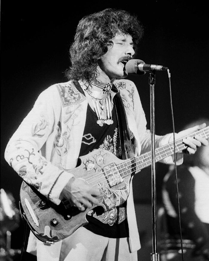 Male celebrity performing live on stage, playing guitar and singing into a microphone during a concert.