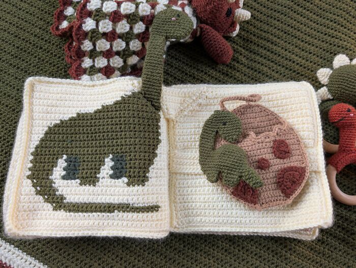 Crocheted dinosaur designs with intricate detail in a handmade book, showcasing advanced crocheting projects and skills.