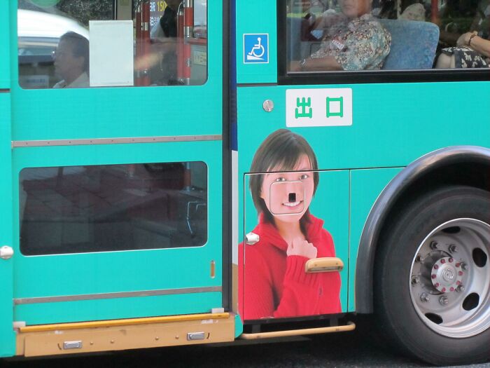 Bus advertisement placement fail shows a woman's face distorted by the handle, illustrating funny advertising placement fails.
