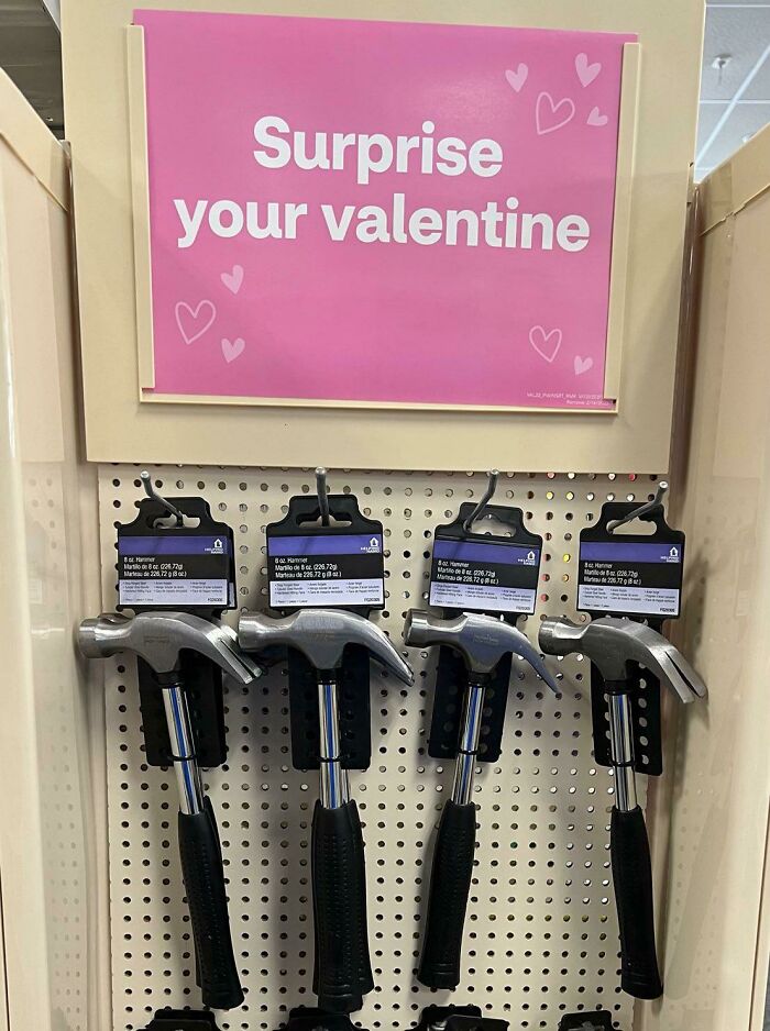 Display of hammers under a pink sign reading surprise your valentine, blending humor with true crime memes for self-care fans.