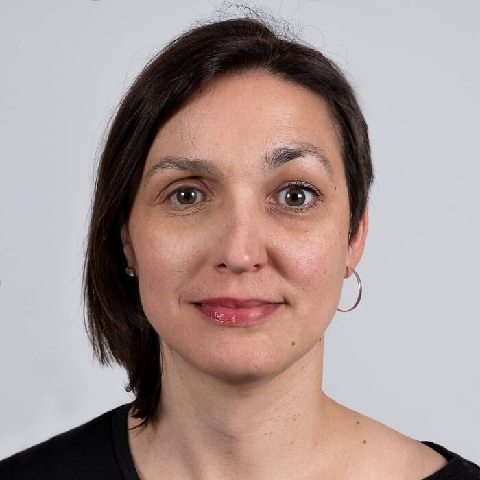 Woman with short dark hair and hoop earrings in a close-up portrait highlighting family DNA resemblance.