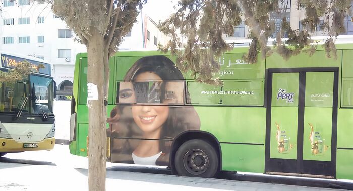 Bus with a makeup advertisement misaligned, creating an advertising placement fail that amuses passersby instead of selling.