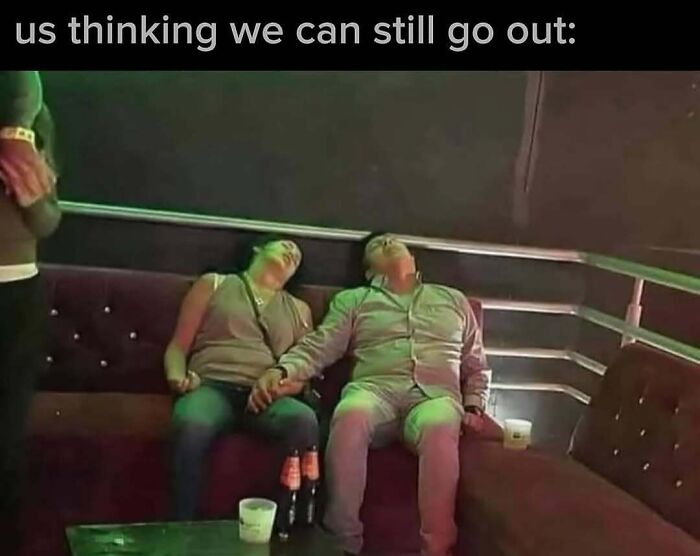 Couple exhausted and leaning back on a couch holding hands in a dim room, relatable funny memes about balancing tough days.