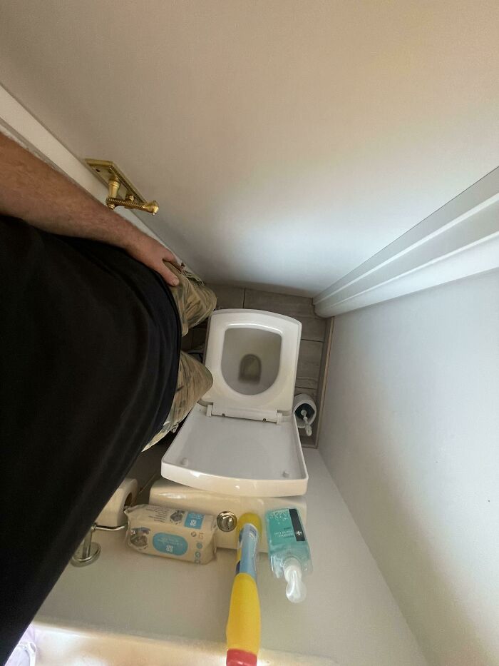 Overhead view of a poorly installed toilet and cleaning tools, showcasing hilariously bad jobs done to get it over with.