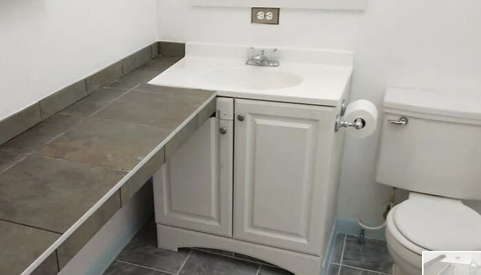 Bathroom vanity with misaligned cabinet doors and poorly finished countertop, showcasing hilariously bad jobs done.
