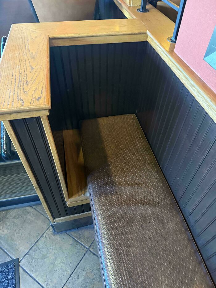 Poorly designed seating area with a bench awkwardly placed inside a wooden booth in a hilariously bad job example.