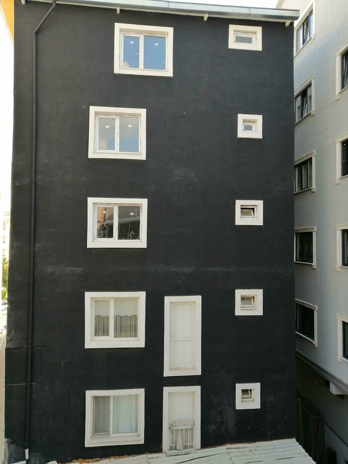 Building facade with mismatched windows and doors, showcasing hilariously bad jobs done with minimal effort.