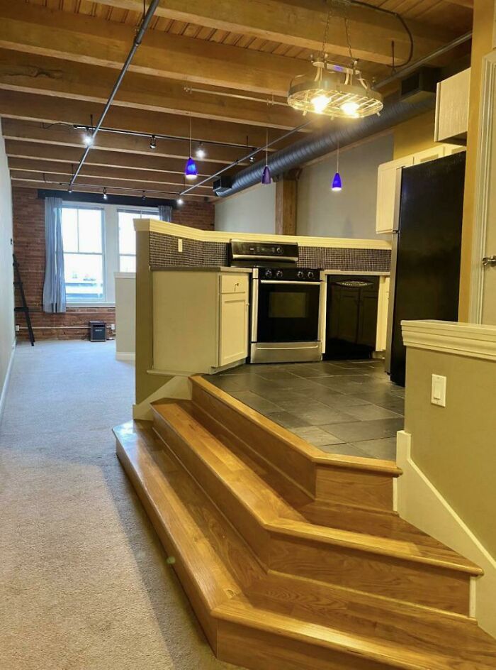 Wooden stairs with uneven steps leading to a kitchen, showing a hilariously bad job done just to get it over with.