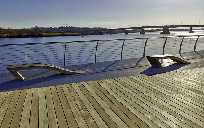 Two poorly designed wooden benches on a waterfront deck showing hilariously bad job craftsmanship.