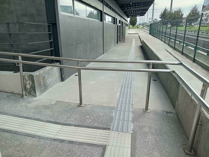 Poorly executed accessibility ramp with metal railings blocking the path, illustrating hilariously bad jobs done carelessly.