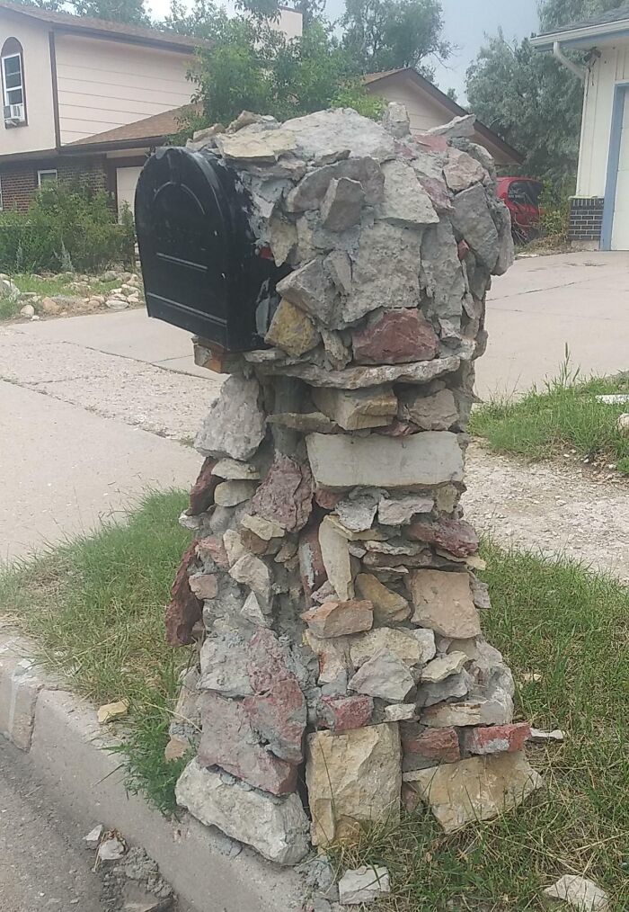 Mailbox with a poorly constructed and uneven stone base showing a hilariously bad job and lack of proper craftsmanship.