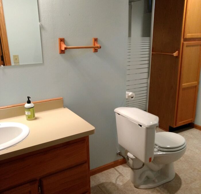 Bathroom with a poorly installed towel rack and toilet paper holder showing hilariously bad job done to get it over with