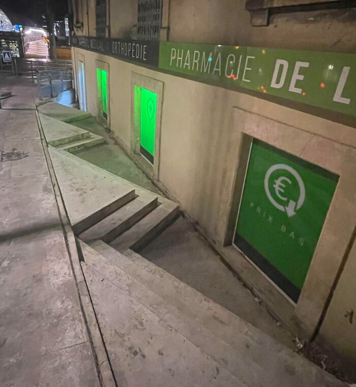 Sidewalk with uneven concrete steps and ramps leading to basement windows, showcasing a hilariously bad job.