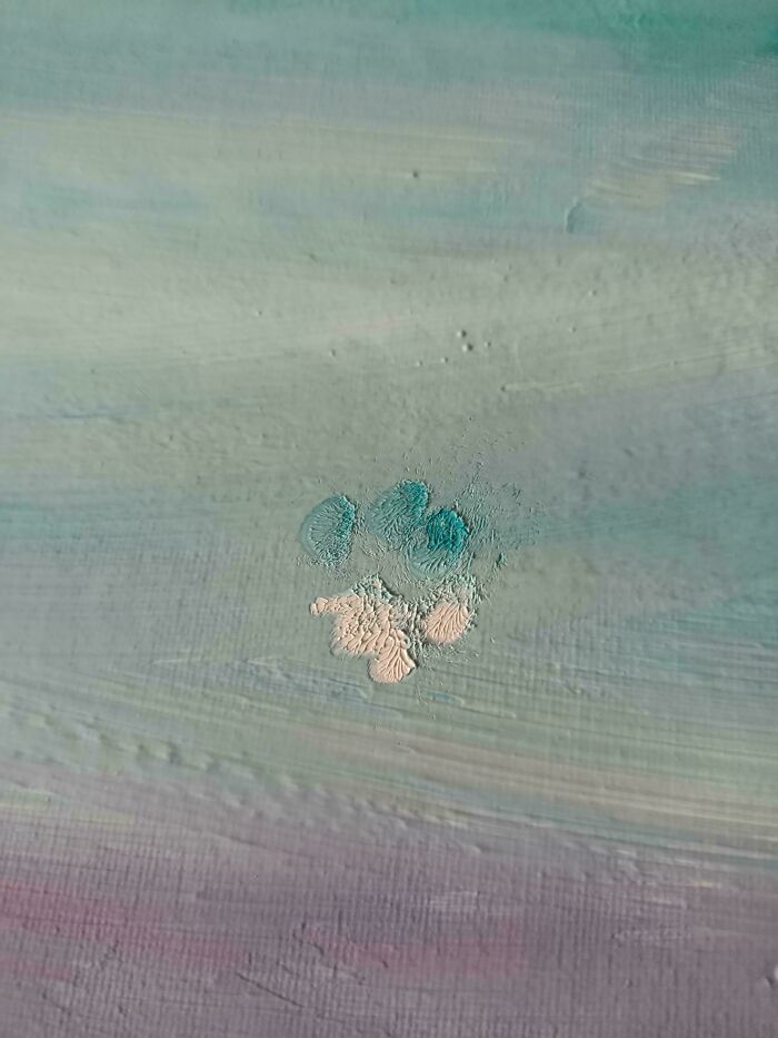 Huella adorable de pata de gato sobre una superficie pintada en tonos pastel mostrando rastros únicos y detallados.