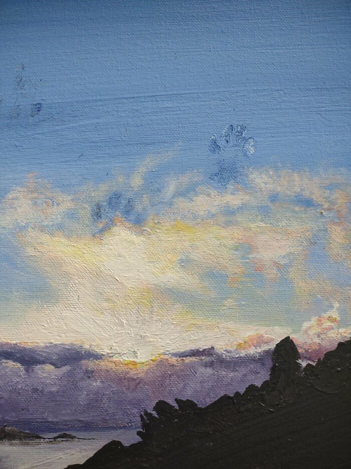 Manchas de huellas de patas de gato sobre un cielo pintado al amanecer con montañas en primer plano.