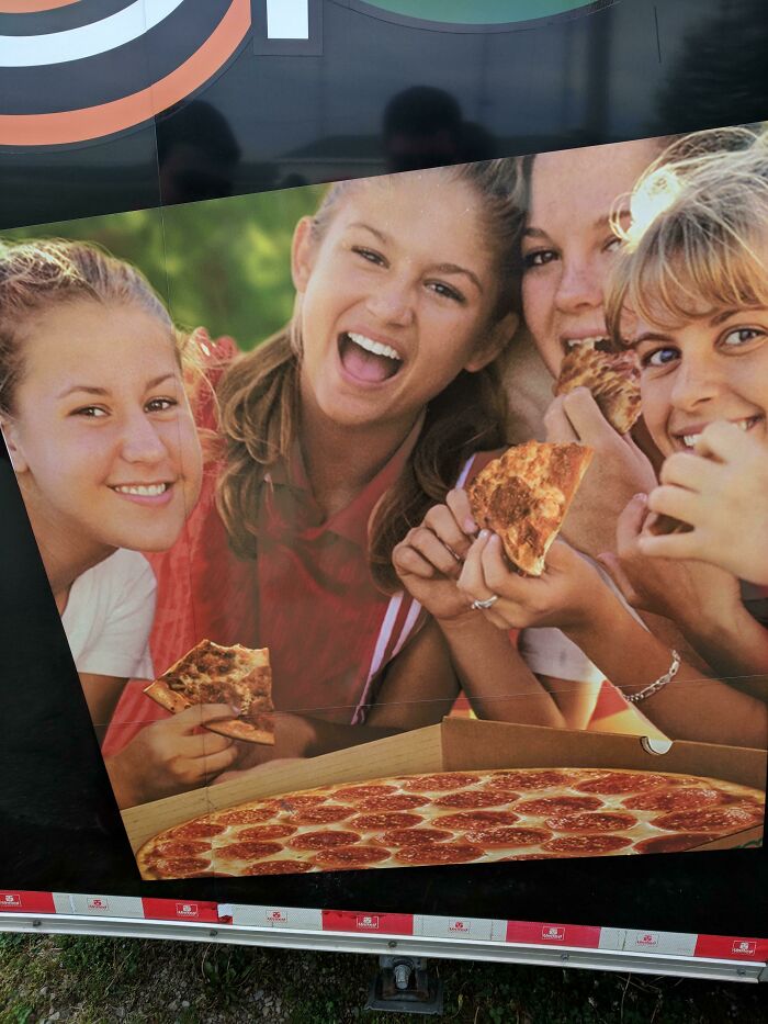 Group of girls eating pizza with an obvious Photoshop fail where extra hands are misplaced on the image.