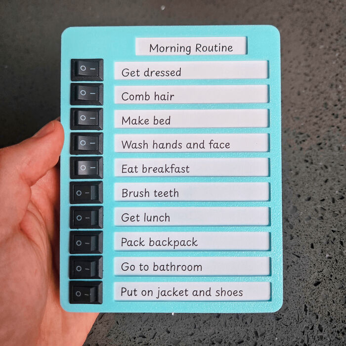 Hand holding a cool handmade morning routine checklist with labeled switches for each task to share with everyone.