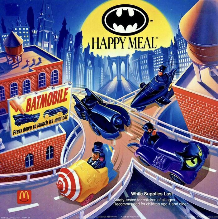 1990s Batmobile Happy Meal toy advertisement featuring mini Batmobile cars on a city rooftop track.