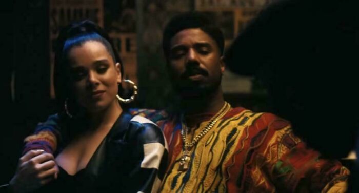 Two people in colorful outfits sitting closely in a dimly lit setting, illustrating bad movie details and confusing scenes.