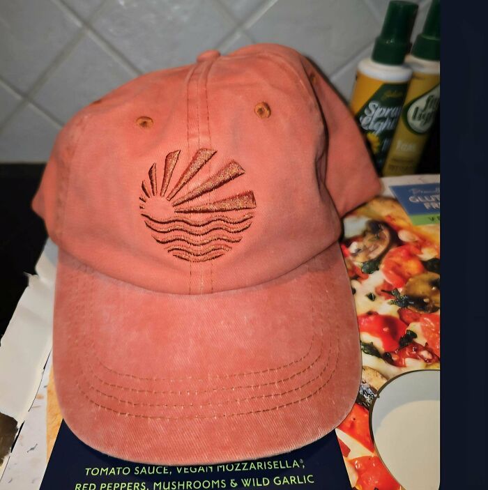A peach-colored baseball cap with an embroidered sun and waves design, showcasing a unique embroidery creation.
