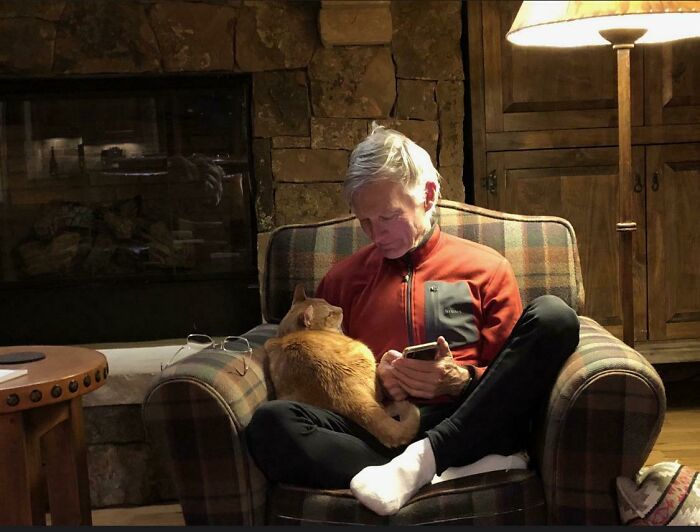 Man in cozy chair with a cat on his lap, showing soft side of dads who said no pets at first.