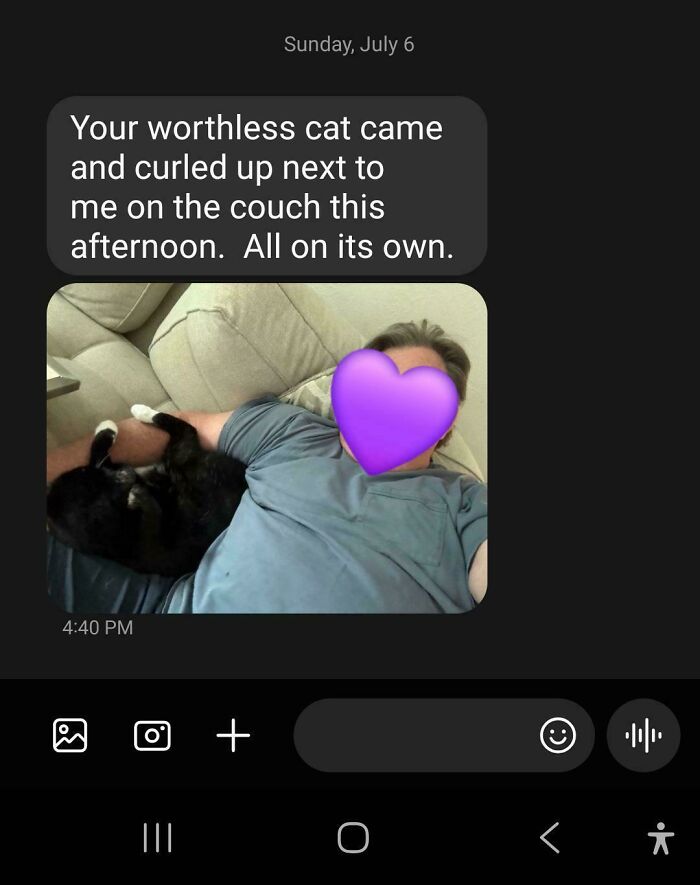 Dad who said no pets cuddling a black cat on the couch, showing dads who became total softies with pets.