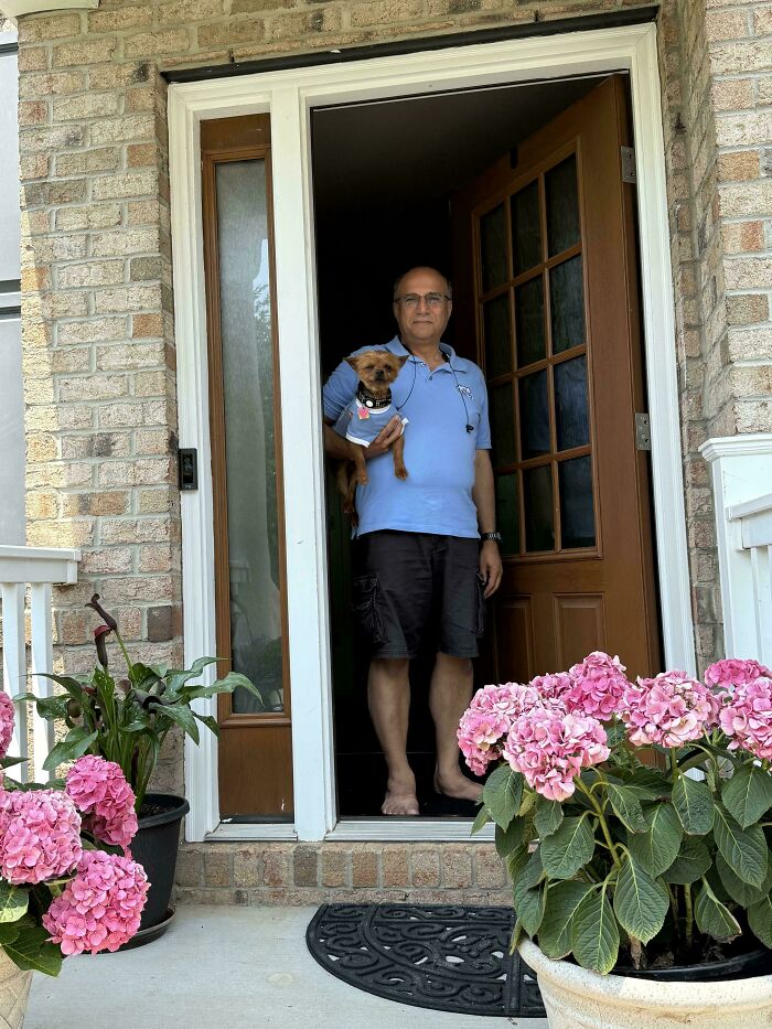 Man holding small dog at front door of house, showing dads who said no pets and became total softies.