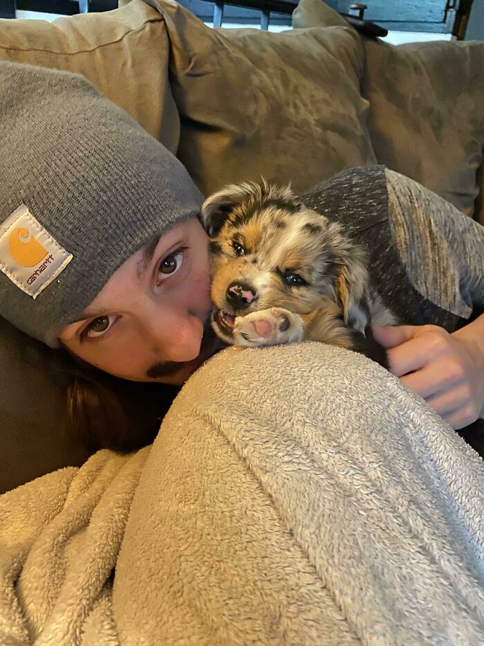 A dad cuddling a puppy on a couch, showing pet love and softening his no pets stance.