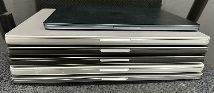 Stack of closed laptops on a desk representing various parts of working in 2025 that are a nightmare for many professionals.