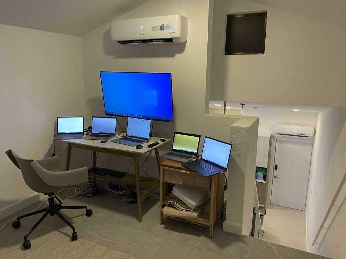 Home office setup with multiple laptops and a large monitor, illustrating the nightmare of working in 2025 parts.