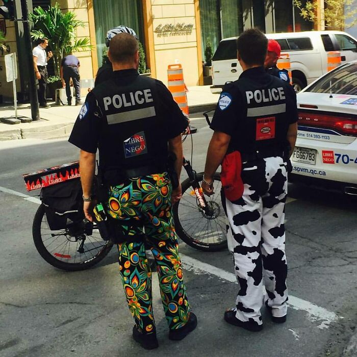 Two police officers wearing colorful and funny patterned pants while standing on a city street in uniform.