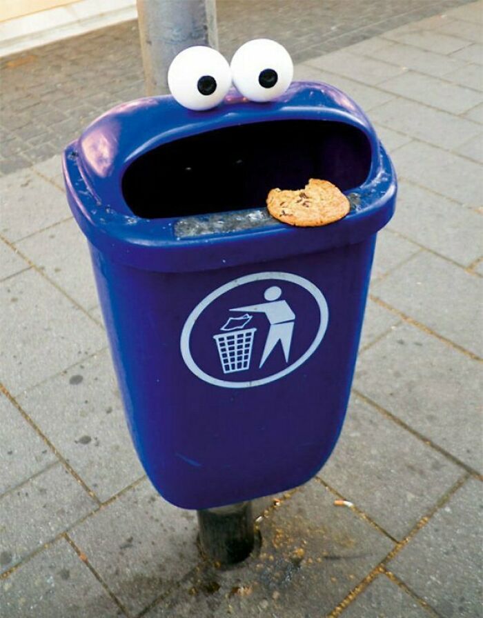Blue trash bin with googly eyes and a cookie, a creative example of vandalized public property art.