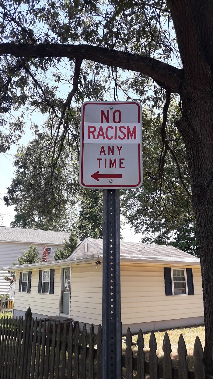 Street sign vandalized to read no racism any time, showing creative public property vandalism against hate.
