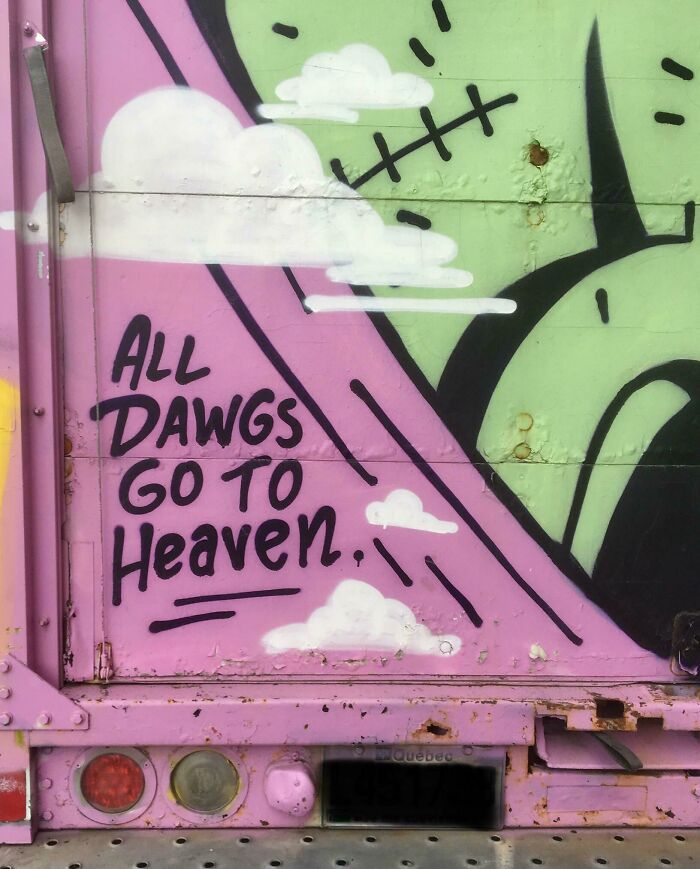 Colorful graffiti on a truck with the phrase all dawgs go to heaven as a creative example of vandalized public property.
