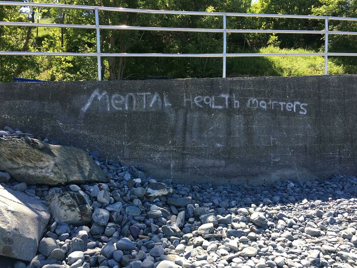 Graffiti on a concrete wall near rocks reads Mental Health matters, an example of vandalized public property.