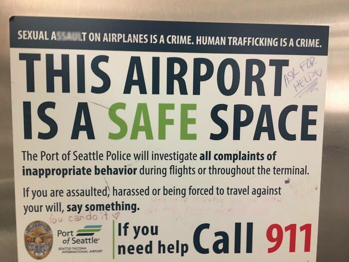 Sign at Seattle airport declaring a safe space with vandalized graffiti, highlighting public property vandalized humorously.