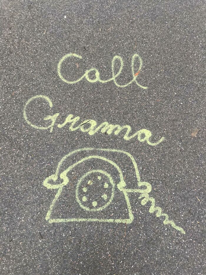 Chalk drawing vandalism on pavement showing a vintage phone and message to call grandma, playful public property art.
