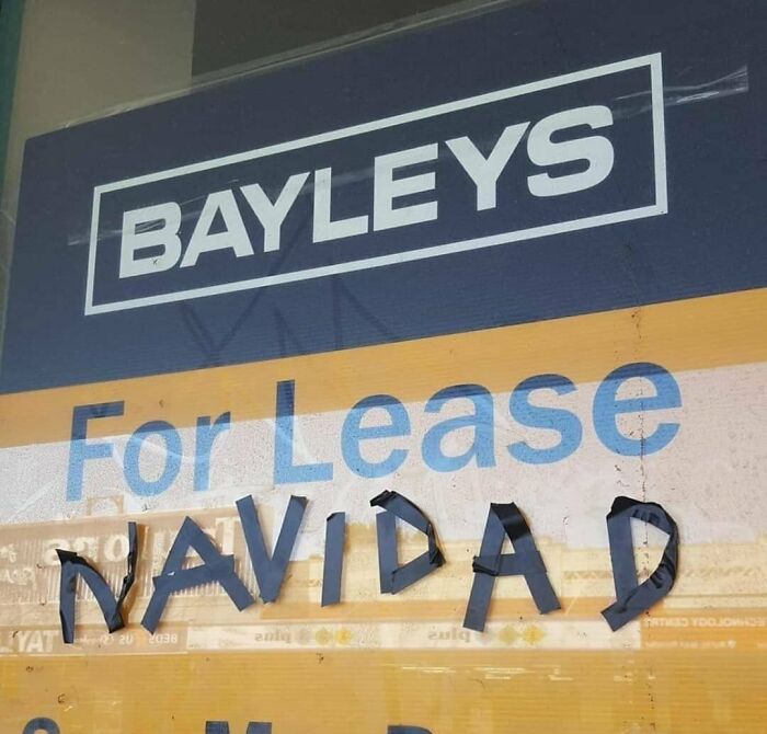 Vandalized public property showing a For Lease sign altered with tape to spell Navidad creatively.