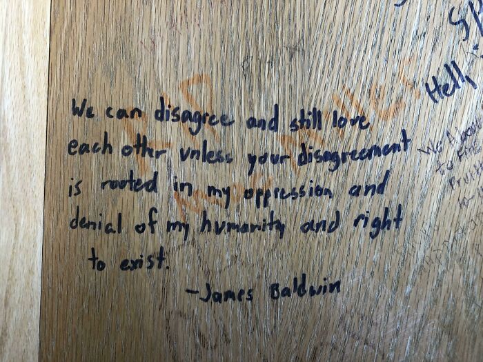 Handwritten message vandalizing public property with a James Baldwin quote about disagreement and humanity.