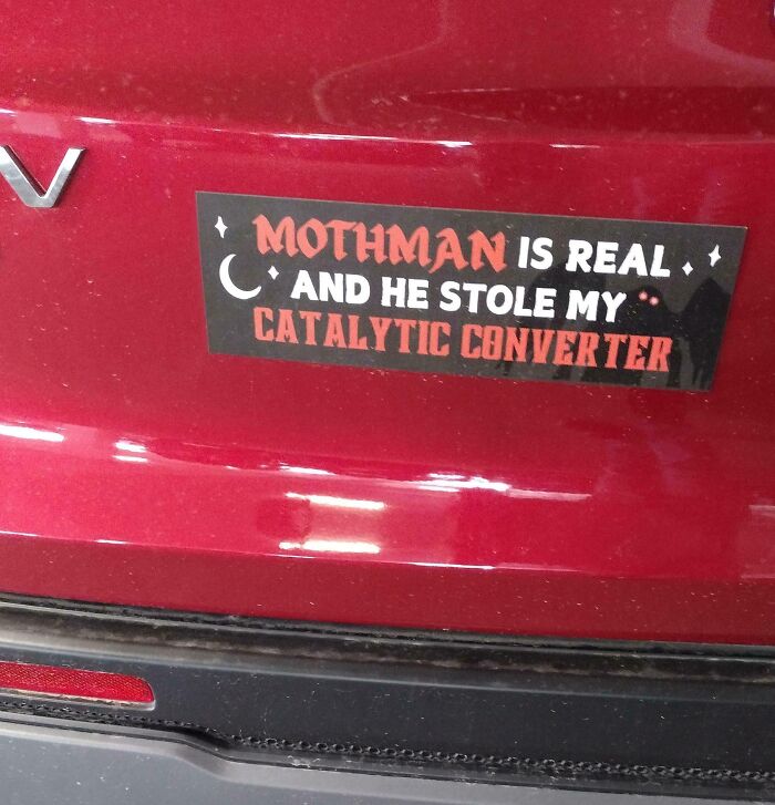 Sticker on red car bumper humorously claiming Mothman stole the catalytic converter, featuring random funny message.