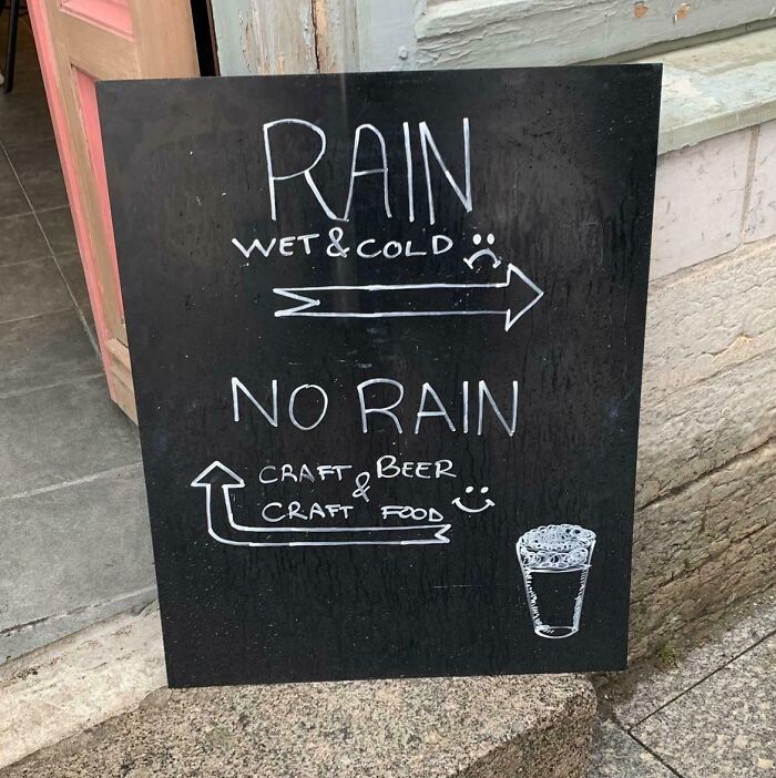 Chalkboard sign with humor about rain directing to craft beer and food, highlighting random notes and messages.