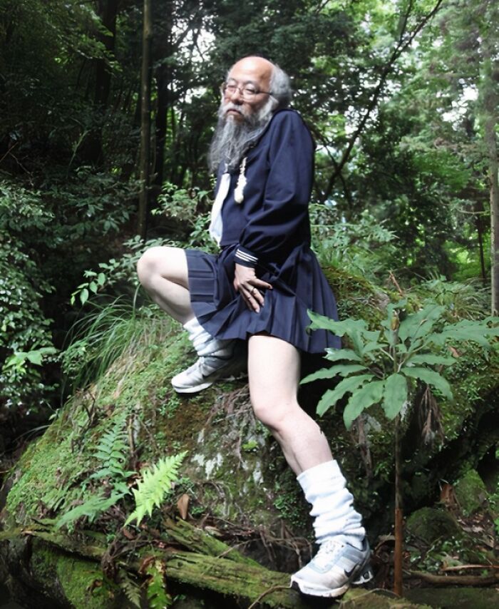 Older man wearing a funny uniform with a skirt and sneakers posing in a forest, showing a humorous take on wearing a uniform.