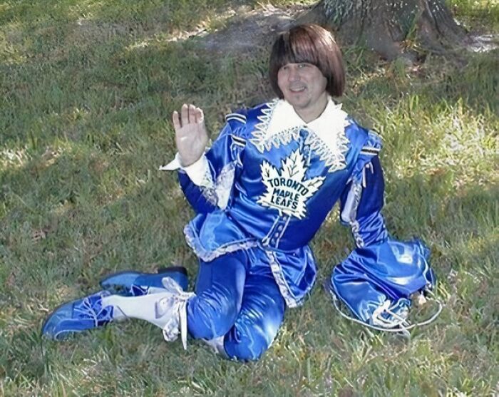 Man posing on grass wearing a shiny blue Toronto Maple Leafs uniform in a funny and playful manner.