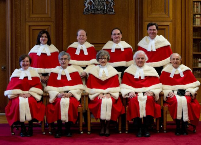 Group of judges wearing traditional red and white robes, showcasing formal uniform attire in an official setting.