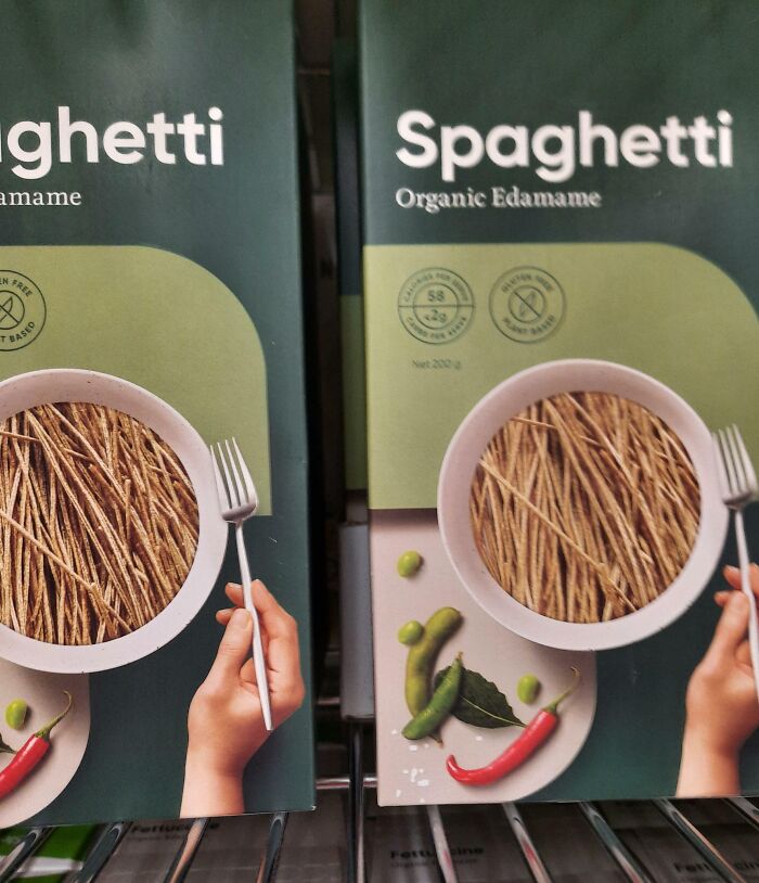 Two boxes of spaghetti with poorly edited images showing a hand holding a fork over a plate of noodles, Photoshop fails.