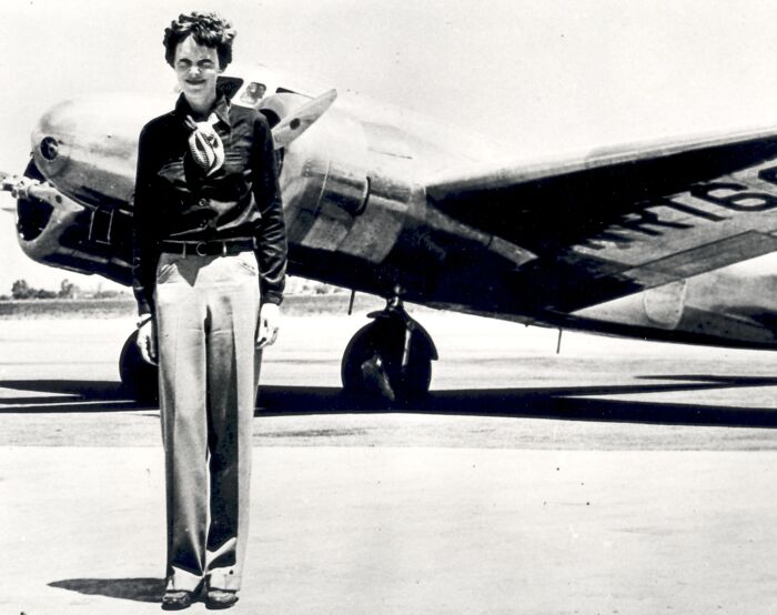 Famous female celebrity pilot standing in front of an old airplane, linked to numerous conspiracy theories and vanished cases.