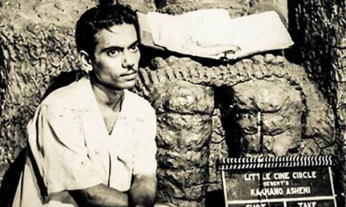 Young man sitting by a stone wall with vintage film slate illustrating celebrities who vanished without a trace conspiracy theories.