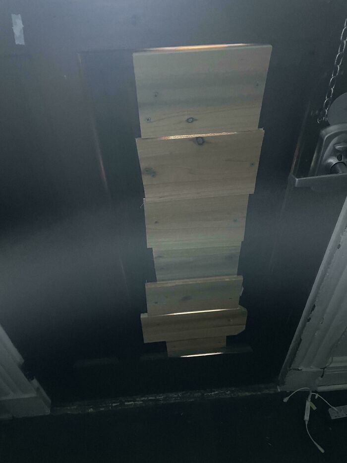 Door blocked with mismatched wooden planks in a rental property, highlighting a landlord's poor maintenance and care.