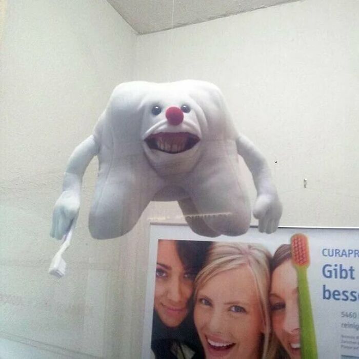 Terrifying tooth-shaped figure with creepy face and toothbrush, creating a frightening and eerie atmosphere.