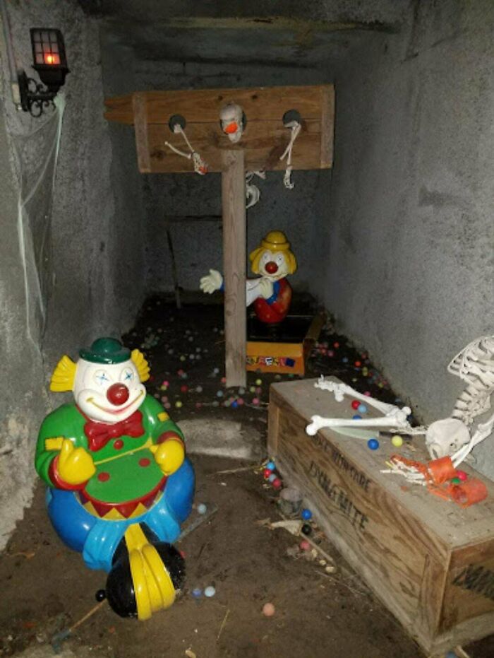 Creepy clown toys and skeleton bones in a dimly lit room creating a terrifying photos scene with eerie atmosphere.